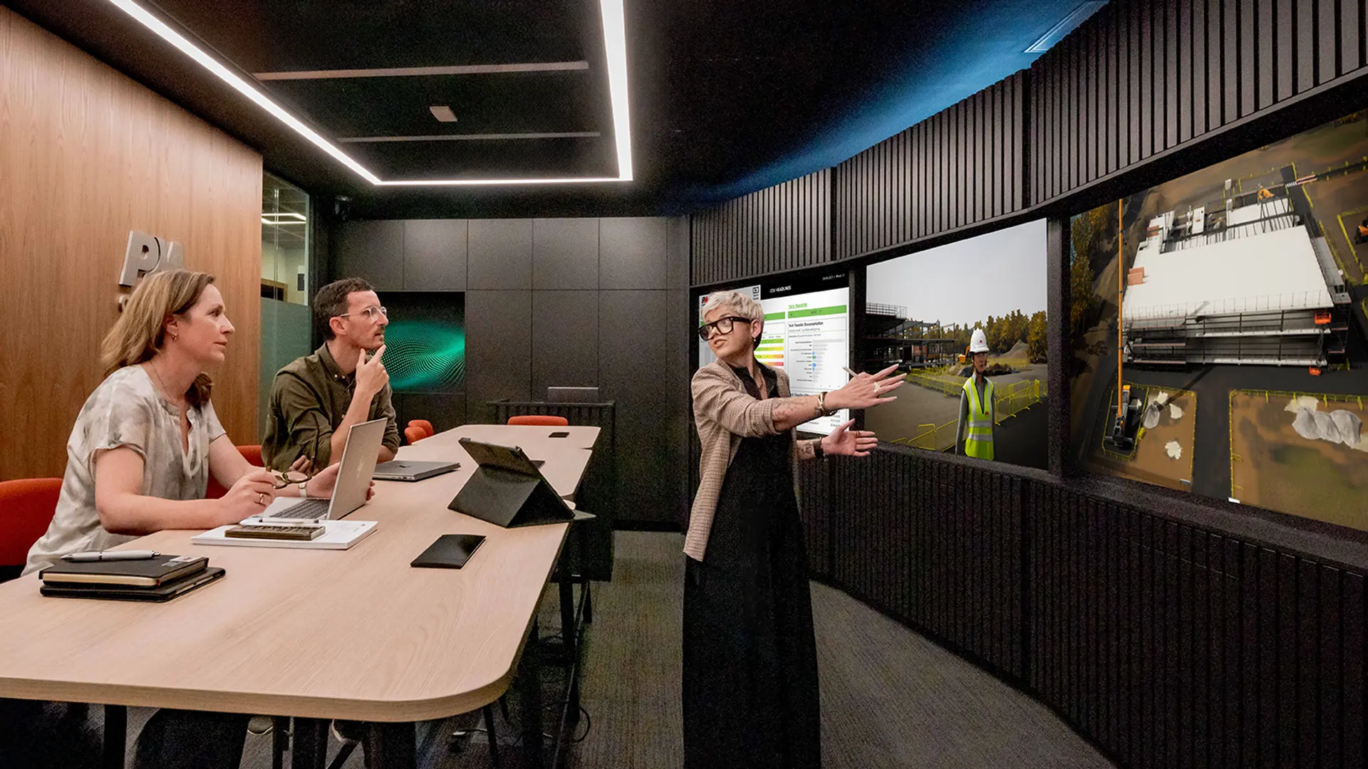 3 people looking at innovative technology on screen in innovation room