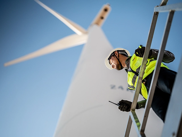 Construction worker on a gantry with a wind turbine in the background